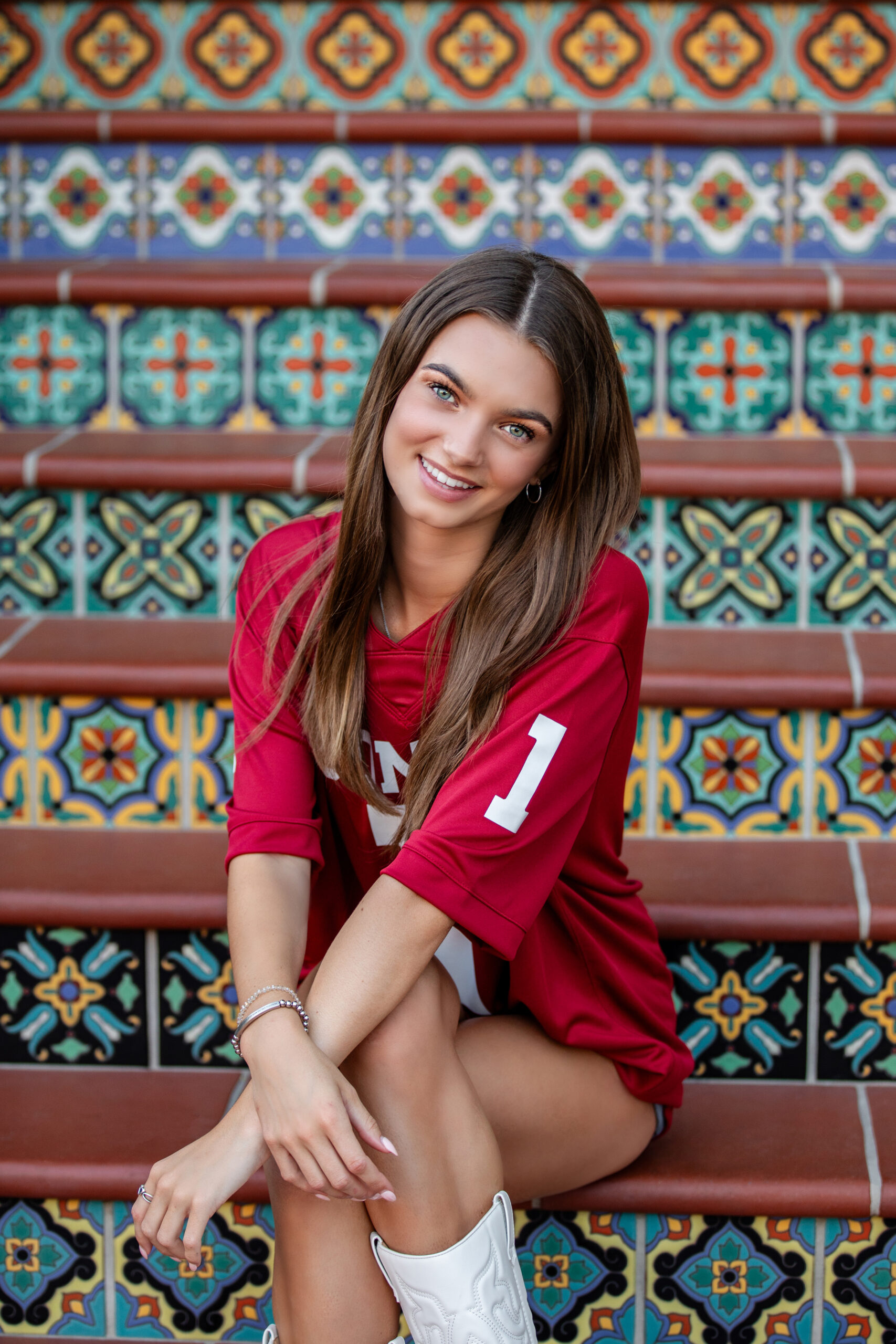 High school senior in a red game-day jersey seated on colorful Spanish-tile steps